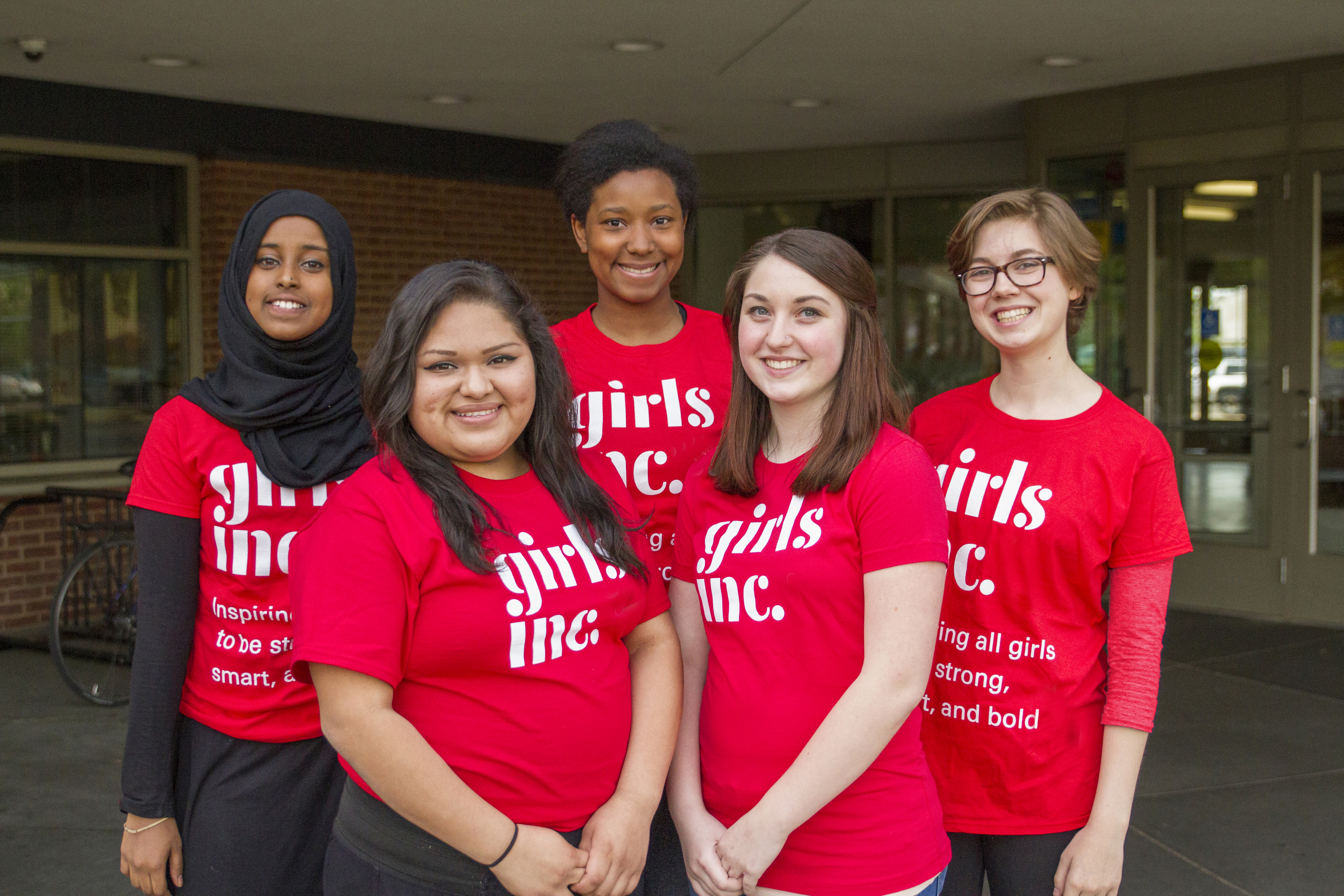 5 smiling women in red shirts posing for a photo